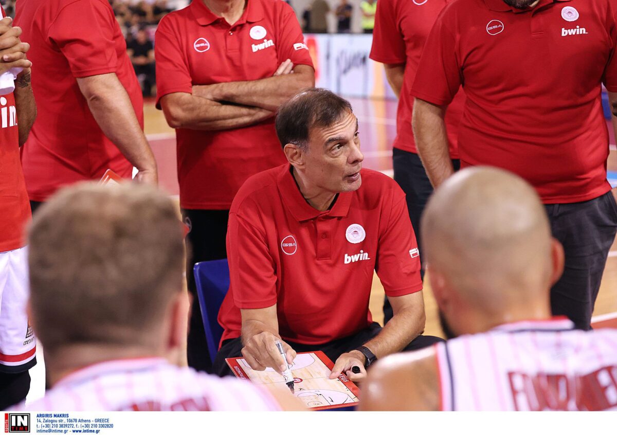 Ο Γιώργος Μπαρτζώκας δίνει οδηγίες στον πάγκο του Ολυμπιακού. Διακρίνονται οι Φουρνιέ και Βεζένκοφ που κάθονται με πλάτη στην κάμερα